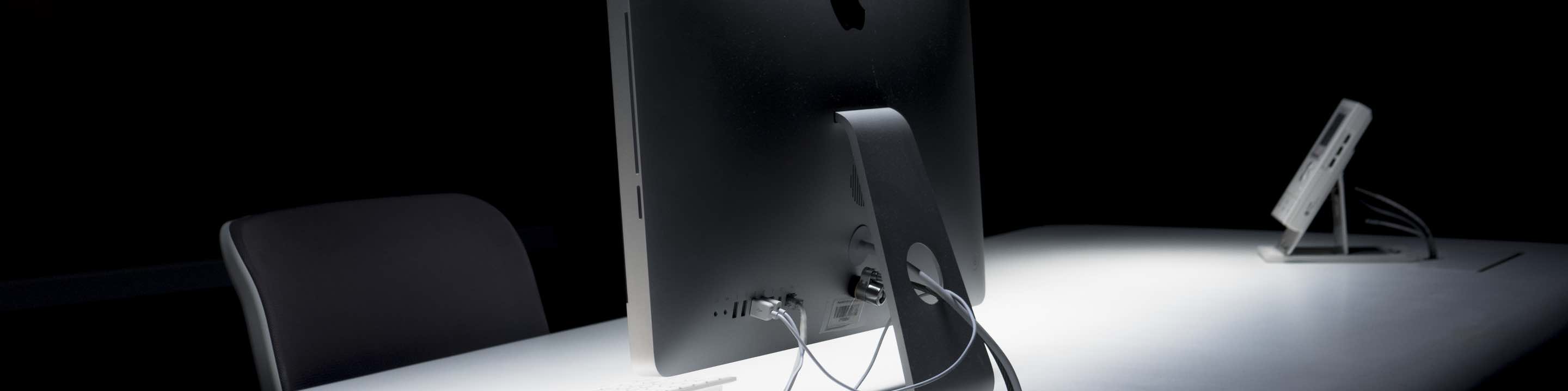dramatically lit empty security desk in the dark with an iMac